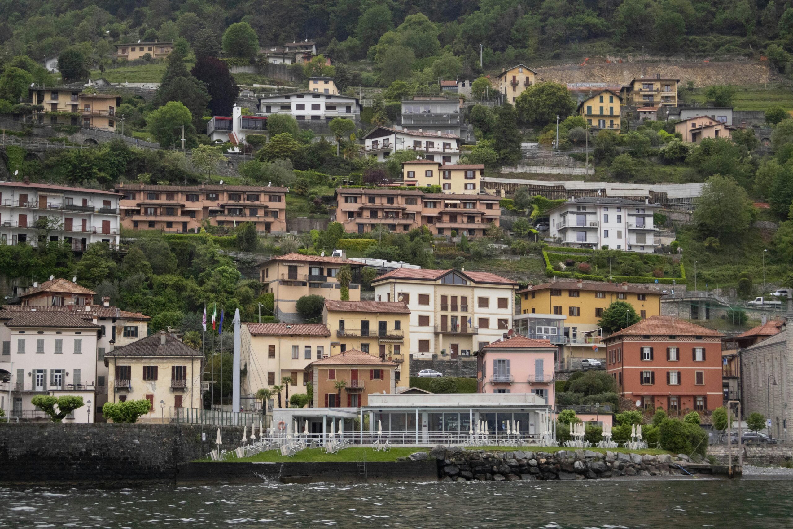 Charming hillside houses by Lake Como with lush greenery in Italy, perfect for travel enthusiasts.