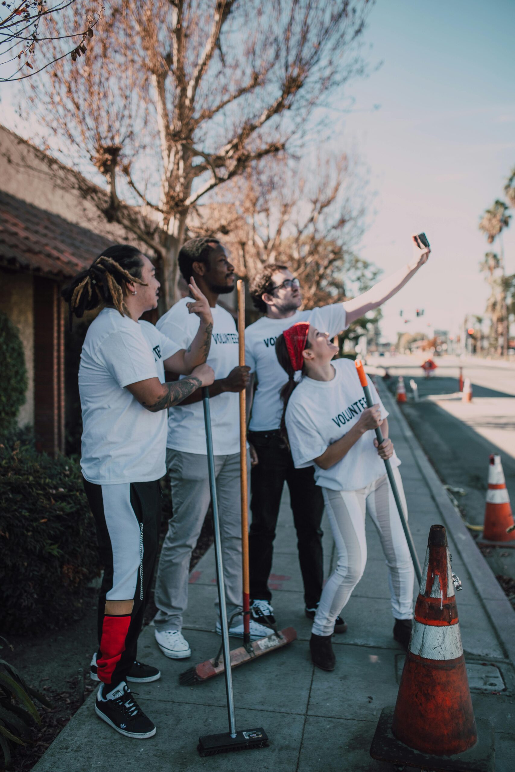 A diverse group of volunteers capturing a group selfie while participating in outdoor community cleaning.